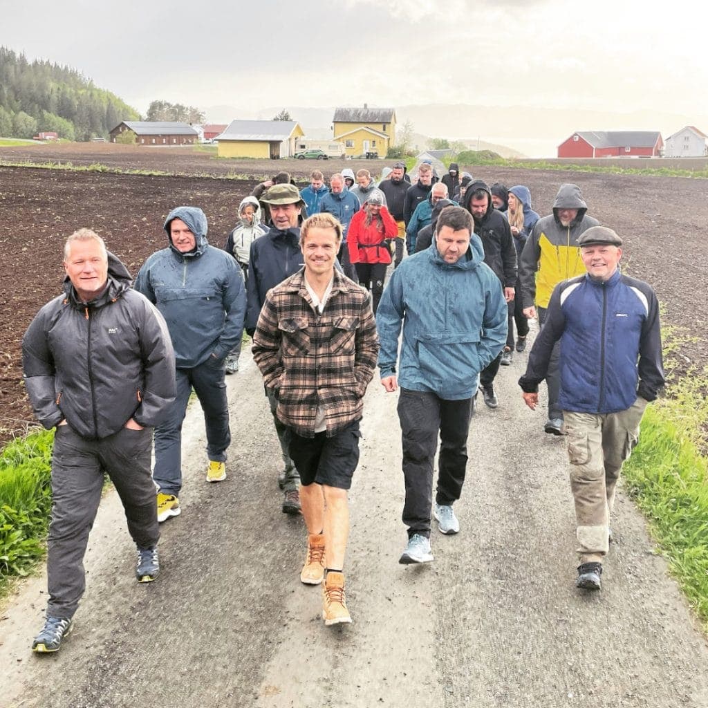 Stor gruppe på walk and talk langs grusveien mellom jordene